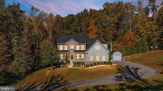 front facade featuring a porch, a garage, a yard, and an outbuilding