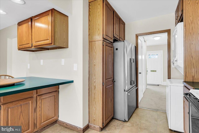 kitchen with high end refrigerator and stacked washing maching and dryer