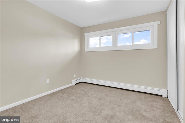 unfurnished room featuring light carpet and a baseboard heating unit