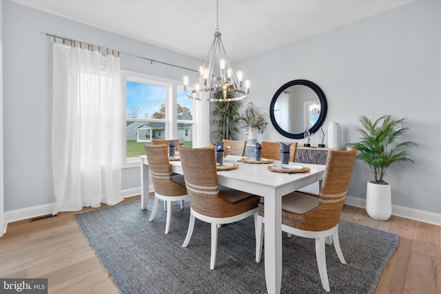 dining room with light wood-type flooring and a notable chandelier