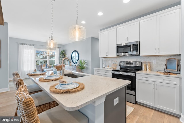 kitchen with white cabinets, sink, an island with sink, and stainless steel appliances