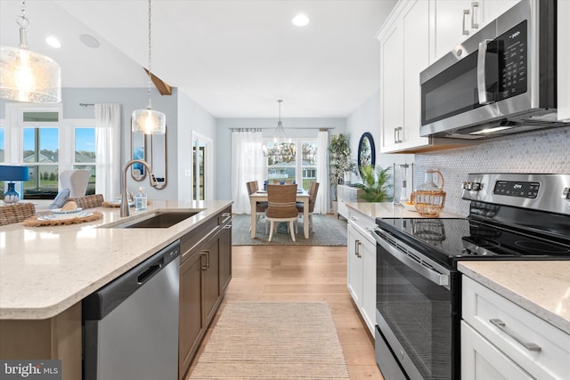 kitchen featuring light hardwood / wood-style floors, white cabinets, hanging light fixtures, and appliances with stainless steel finishes