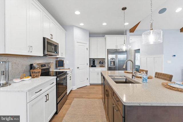 kitchen with appliances with stainless steel finishes, white cabinetry, pendant lighting, and sink