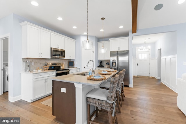 kitchen with stainless steel appliances, sink, light hardwood / wood-style flooring, white cabinetry, and an island with sink