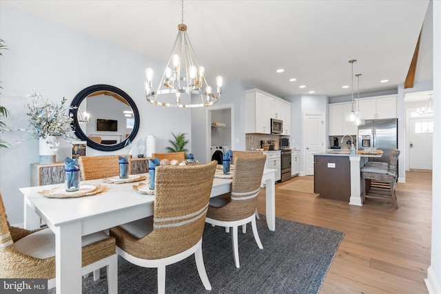 dining area featuring light wood-type flooring, sink, and a chandelier