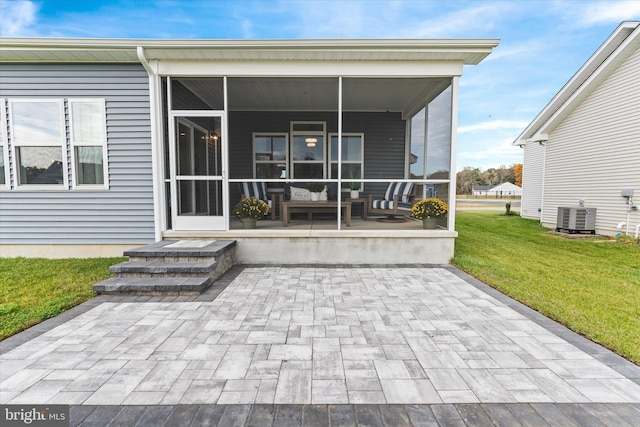 rear view of property featuring an outdoor living space, central AC unit, a patio area, a sunroom, and a yard