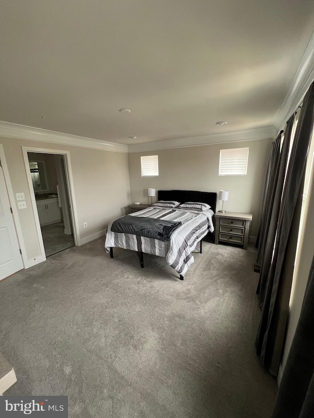 carpeted bedroom featuring ornamental molding and ensuite bath