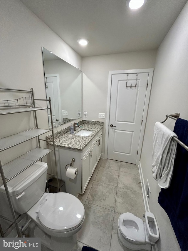 bathroom with tile patterned flooring, vanity, and toilet