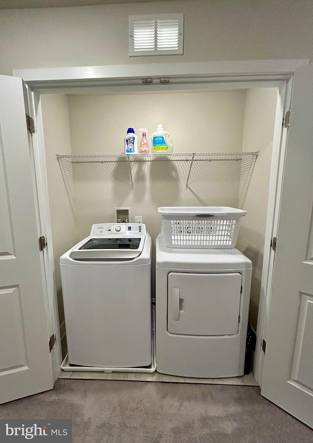 washroom with washing machine and dryer and light carpet