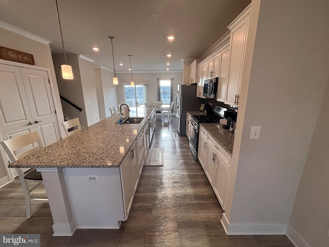 kitchen featuring a breakfast bar, stainless steel appliances, white cabinetry, hanging light fixtures, and a large island