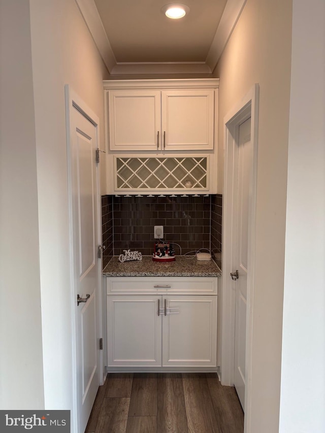 bar featuring white cabinets, dark hardwood / wood-style floors, dark stone counters, and tasteful backsplash