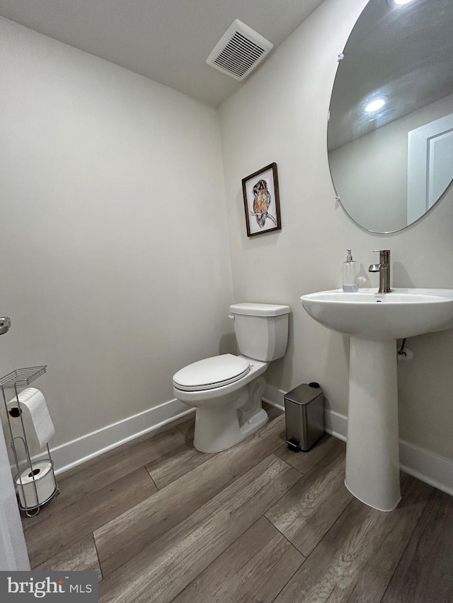 bathroom with hardwood / wood-style flooring, toilet, and sink