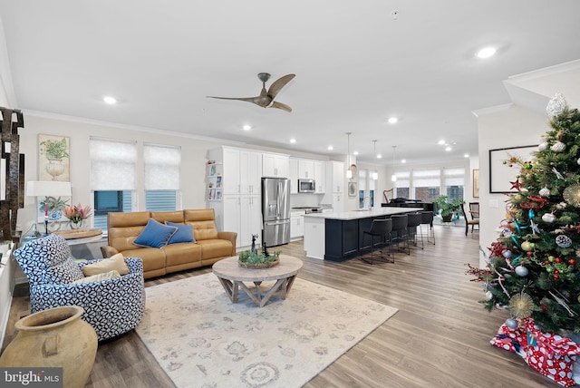 living room featuring ceiling fan, light hardwood / wood-style floors, plenty of natural light, and crown molding