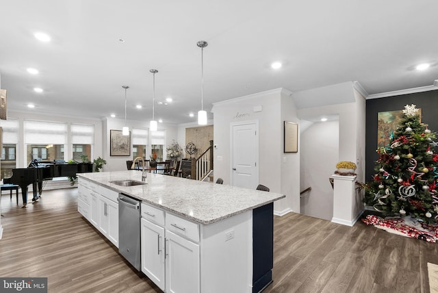 kitchen featuring a kitchen island with sink, sink, hardwood / wood-style flooring, white cabinets, and hanging light fixtures