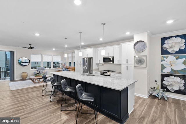 kitchen with white cabinetry, ceiling fan, hanging light fixtures, light hardwood / wood-style flooring, and appliances with stainless steel finishes