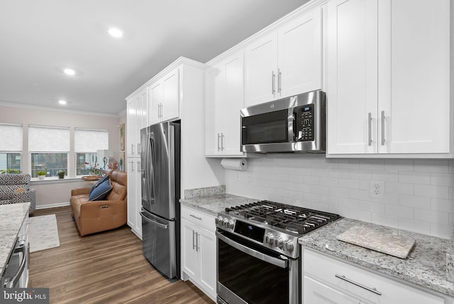 kitchen featuring light stone countertops, white cabinetry, ornamental molding, and appliances with stainless steel finishes