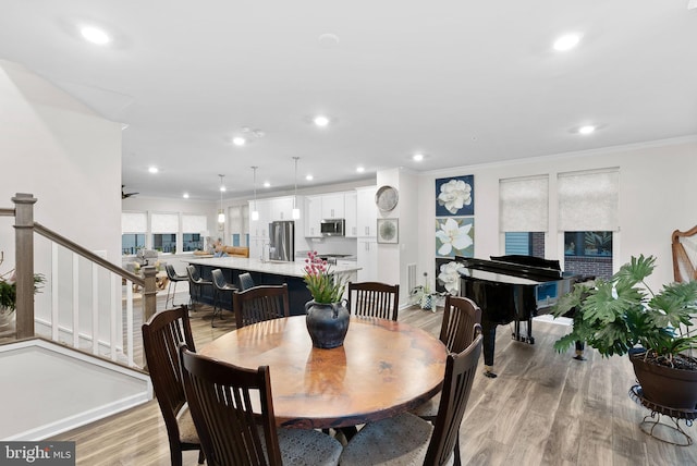 dining space featuring light wood-type flooring, ceiling fan, and crown molding