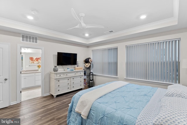 bedroom with ceiling fan, dark hardwood / wood-style flooring, connected bathroom, and a tray ceiling