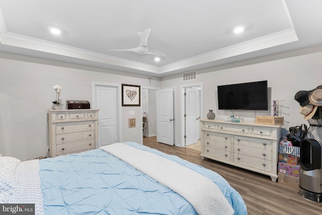 bedroom featuring dark hardwood / wood-style flooring, a raised ceiling, ceiling fan, and ornamental molding