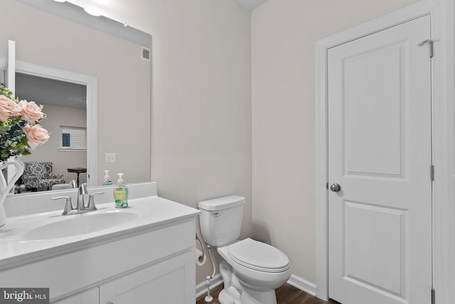 bathroom with hardwood / wood-style floors, vanity, and toilet