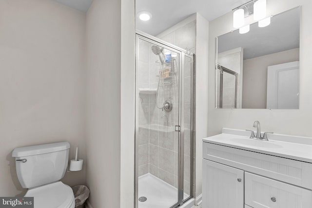 bathroom featuring vanity, a shower with shower door, and toilet