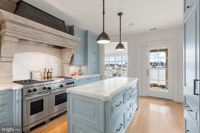 kitchen with double oven range, hanging light fixtures, light hardwood / wood-style floors, a kitchen island, and custom exhaust hood