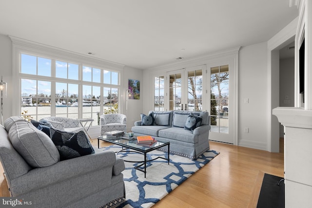 living room featuring crown molding, light wood-type flooring, and french doors