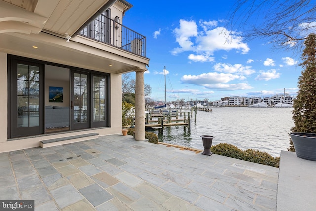 dock area with a water view, a balcony, and a patio area