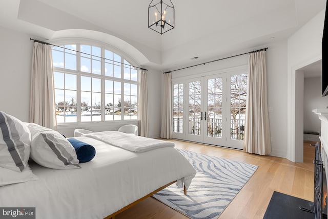 bedroom featuring access to outside, a notable chandelier, light wood-type flooring, and french doors