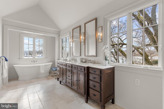 bathroom with vaulted ceiling, vanity, and a tub