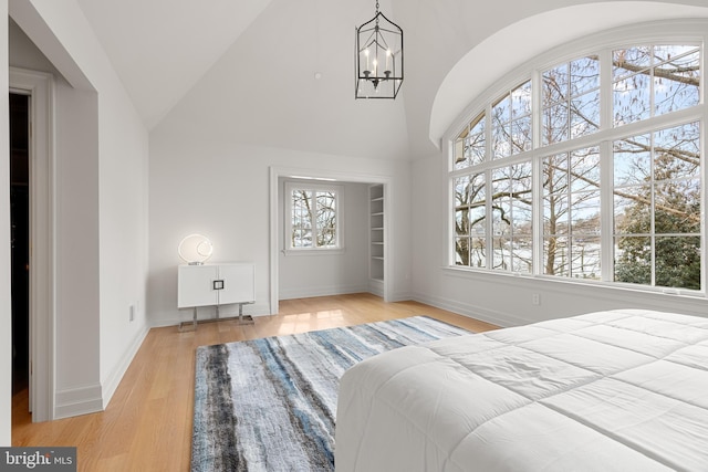 bedroom featuring high vaulted ceiling, a chandelier, and light hardwood / wood-style floors