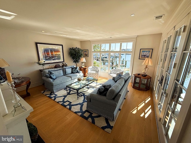 living room with wood-type flooring, a wall of windows, french doors, and a water view