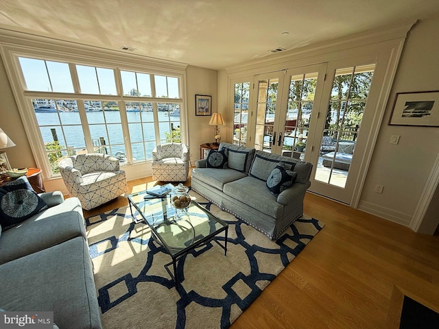 living room with light hardwood / wood-style flooring, french doors, and a water view