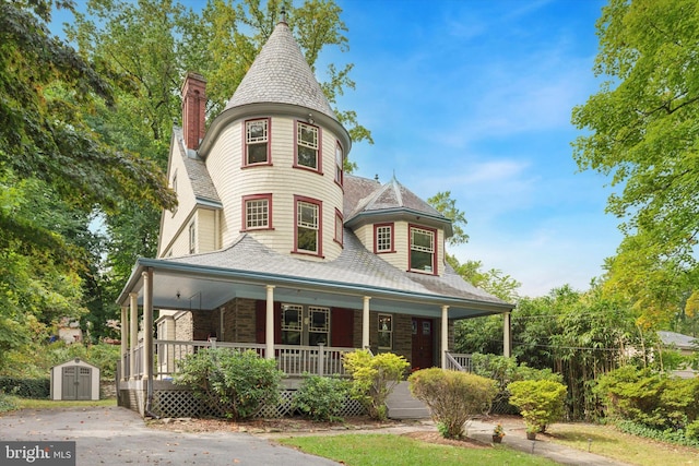 victorian home with a porch and a storage shed