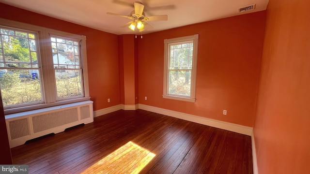 empty room featuring hardwood / wood-style flooring, ceiling fan, and radiator heating unit