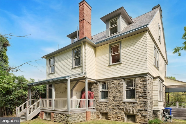 rear view of house with a porch and a yard