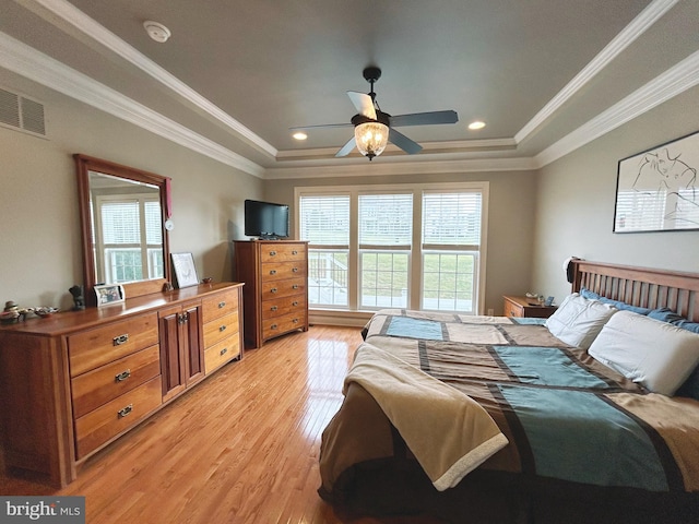 bedroom featuring ceiling fan, light hardwood / wood-style floors, ornamental molding, and a tray ceiling