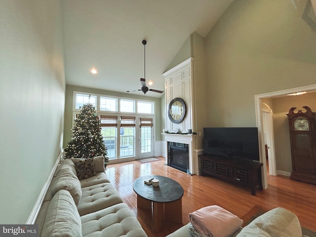 living room featuring ceiling fan, high vaulted ceiling, and light wood-type flooring