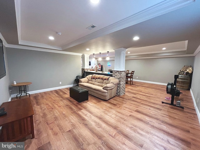 living room with a raised ceiling, ornate columns, light hardwood / wood-style flooring, and ornamental molding