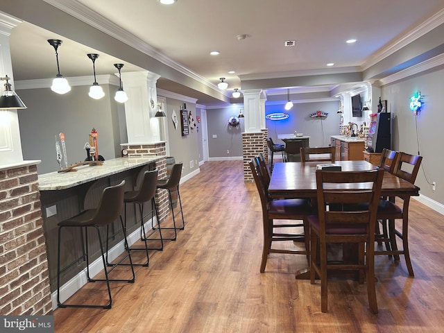 dining space featuring decorative columns, crown molding, and light hardwood / wood-style flooring