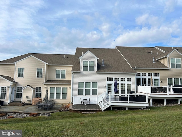 rear view of property featuring a deck, a patio area, and a lawn