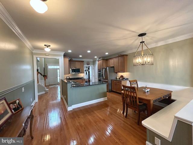 kitchen featuring dark hardwood / wood-style flooring, ornamental molding, stainless steel appliances, a chandelier, and hanging light fixtures