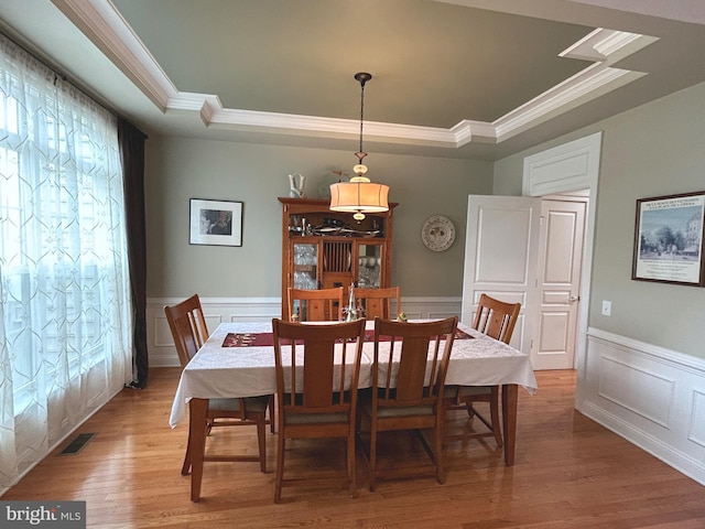 dining room with a raised ceiling, crown molding, and hardwood / wood-style flooring