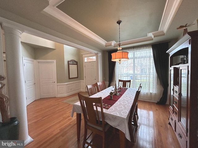 dining space featuring hardwood / wood-style flooring, a raised ceiling, and crown molding