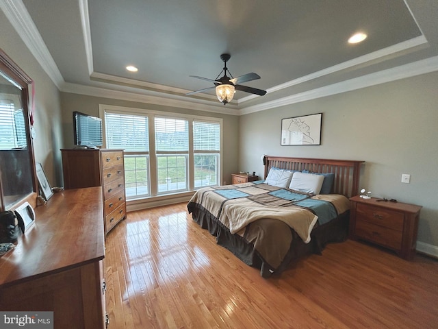 bedroom featuring a tray ceiling, crown molding, ceiling fan, and light hardwood / wood-style floors