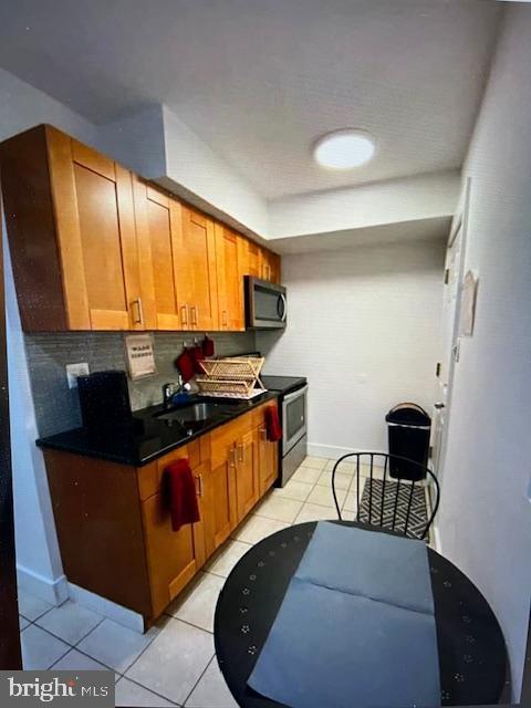 kitchen with decorative backsplash, appliances with stainless steel finishes, light tile patterned floors, and sink