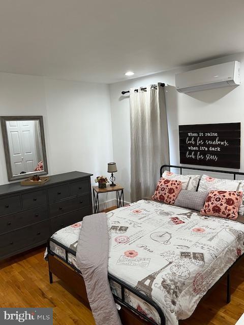 bedroom featuring light hardwood / wood-style flooring and a wall mounted air conditioner