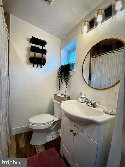 bathroom with hardwood / wood-style floors, vanity, and toilet