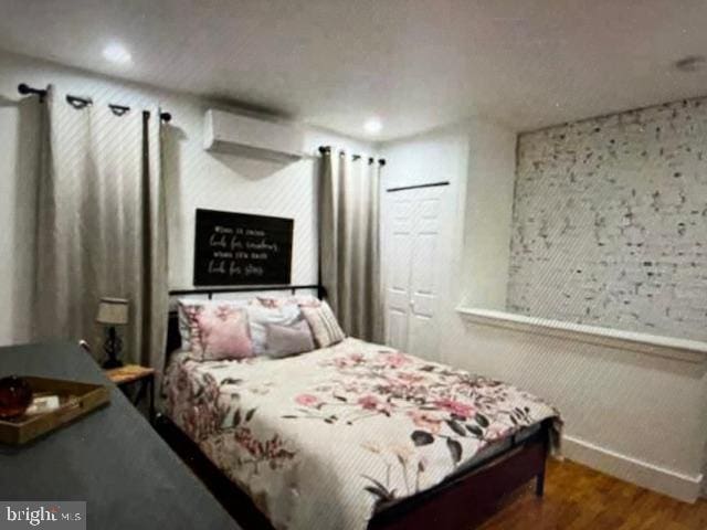 bedroom featuring wood-type flooring and a wall unit AC