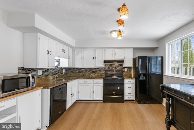 kitchen featuring light wood-type flooring, sink, black appliances, white cabinets, and hanging light fixtures